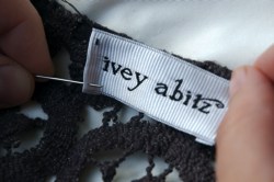 Sewing on an Ivey Abitz label.