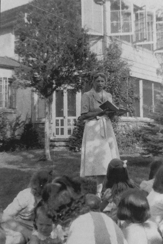 Eleanor often invited local school children to Val-Kill for picnics and storytime. Here she is reading a book in front of Val-Kill Cottage. Photograph courtesy National Park Service.