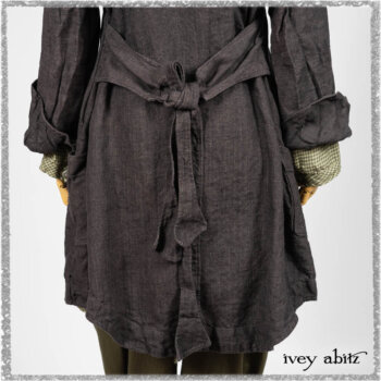 Chevallier Duster Coat in Anchor Grey Wondrous Washed Linen; Chevallier Shirt in Seagrass Petite Check Linen; Chevallier Trousers in Seagrass Herringbone Twill with contrasting lacing to match shirt; Clotaire Sash in Pointillism Silk Chiffon. Ivey Abitz bespoke clothing.