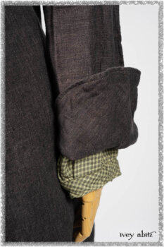 Chevallier Duster Coat in Anchor Grey Wondrous Washed Linen; Chevallier Shirt in Seagrass Petite Check Linen; Chevallier Trousers in Seagrass Herringbone Twill with contrasting lacing to match shirt; Clotaire Sash in Pointillism Silk Chiffon. Ivey Abitz bespoke clothing.
