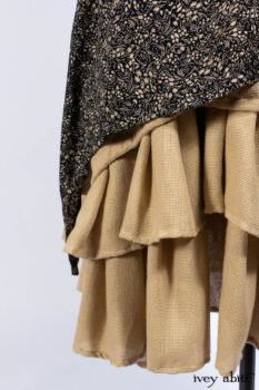 Baudelaire Duster Coat in Mansard Roof and Sandstone Washed Crepe; Delphine Dress in Mansard Roof and Sandstone Sprig Silk Chiffon; Lydia Neck Wrap and Lydia Arm Sleeves in Signature Black Washed Knit; Everett Frock in Sandstone Washed Weave.
