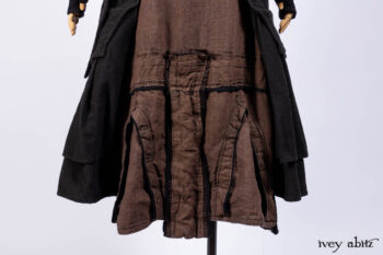 Everett Duster Coat in Mansard Roof Coat Weave; Lydia Neck Wrap and Lydia Arm Wraps in Signature Black Washed Knit; Roebling Frock in Brownstone Washed Linen; Cilla Slip Frock in Signature Black Washed Knit.