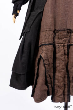 Everett Duster Coat in Mansard Roof Coat Weave; Lydia Neck Wrap and Lydia Arm Wraps in Signature Black Washed Knit; Roebling Frock in Brownstone Washed Linen; Cilla Slip Frock in Signature Black Washed Knit.