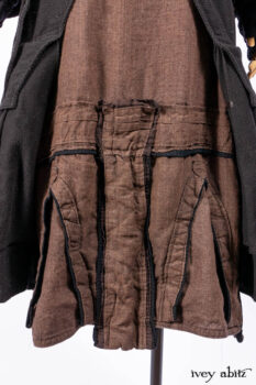 Everett Duster Coat in Mansard Roof Coat Weave; Lydia Neck Wrap and Lydia Arm Wraps in Signature Black Washed Knit; Roebling Frock in Brownstone Washed Linen; Cilla Slip Frock in Signature Black Washed Knit.