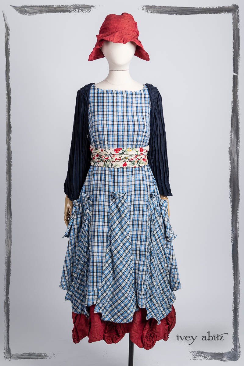 Vallonné Jacket in Bastille Blue Flutter Pleat Knit; Furtherafield Frock in Seaside Woven Plaid; Porte Cochere Sash in Poppy Garden Weave; Bartholdi Frock in Poppy Washed Linen; Hapgood Hat in Poppy Washed Linen. Bespoke clothing by Ivey Abitz.