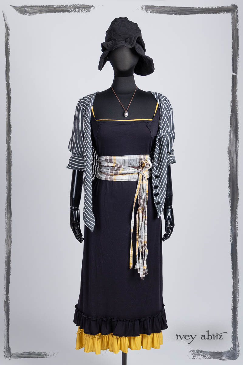 Limited Edition Gilbert Cardigan in Noir and Blanche Stretch Stripe; Porte Cochere Sash in Clapboard Cottage Washed Plaid, Hapgood Hat in Noir Puckered Knit;  Essentielle Frock in Marigold Plant Based Knit; Essentielle Frock in Noir Washed Silk Jersey Knit; Nouvelle Necklace. Bespoke clothing by Ivey Abitz.