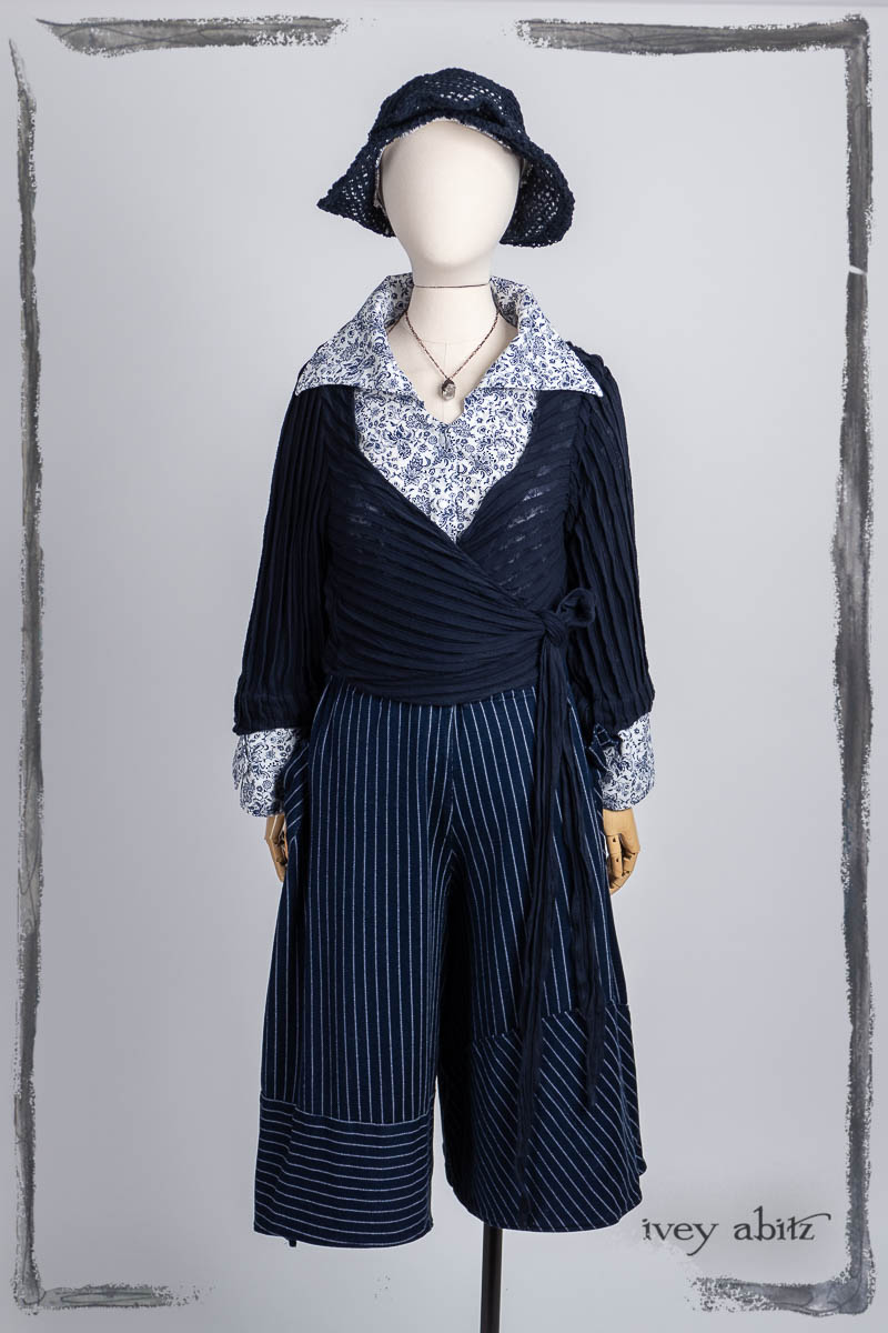 Vallonné Jacket in Bastille Blue Flutter Pleat Knit; Baedeker Shirt in Bastille Blue Fleur Cotton; Cossart Culottes in Bastille Blue Stripe Knit; Hapgood Hat in Bastille Blue Open Weave Knit; Nouvelle Necklace. Bespoke clothing by Ivey Abitz.