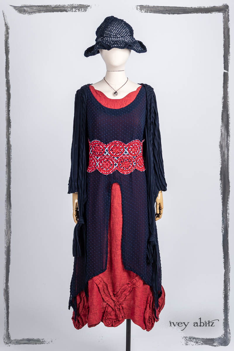 Vallonné Jacket in Bastille Blue Flutter Pleat Knit; Pique-nique Sash in Bastille Blue and Poppy Embroidered Weave; Lumiere Frock in Bastille Blue Tufted Dot Silk Chiffon; Bartholdi Frock in Poppy Washed Linen; Hapgood Hat in Bastille Blue Open Weave Knit; Nouvelle Necklace. Bespoke clothing by Ivey Abitz.