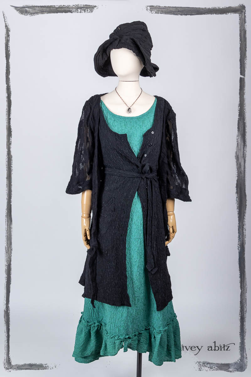 Vallonné Jacket in Noir Embroidered Lace Knit; Ellis Frock in Noir Puckered Washed Silk; Tilbrook Frock in Veranda Puckered Washed Silk; Hapgood Hat in Noir Puckered Knit; Nouvelle Necklace. Bespoke clothing by Ivey Abitz.