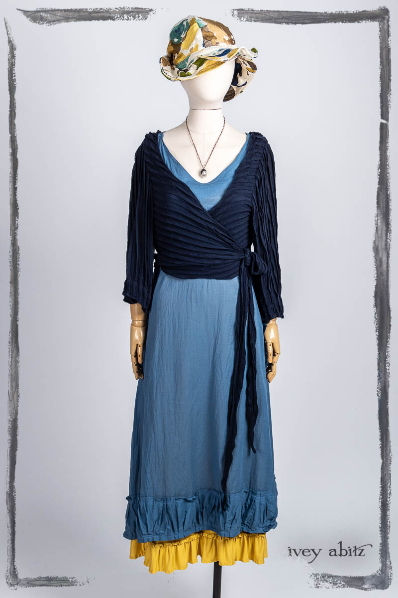 Vallonné Jacket in Bastille Blue Flutter Pleat Knit; Gabled Frock in Bluebell Washed Batiste; Essentielle Frock in Marigold Plant Based Knit; Hapgood Hat in Floral Embroidered Weave; Nouvelle Necklace. Bespoke clothing by Ivey Abitz.