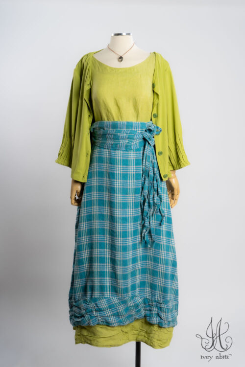 Lydia Jacket in Avocado Soft and Stretchy Knit; Lydia Shirt in Avocado Soft and Stretchy Knit; Fitzgerald Skirt in Turquoise Woven Plaid; Porte Cochere Sash in Turquoise Woven Plaid; Nouvelle Necklace.