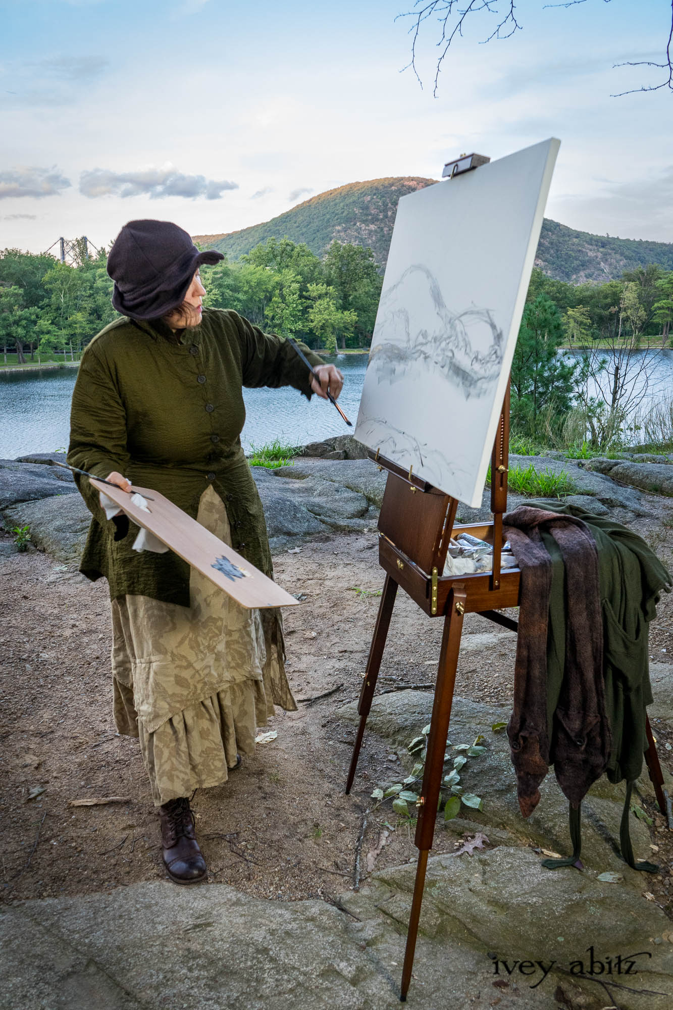 Cynthia Ivey Abitz painting Anthony's Nose and Hessian Lake on location. Ellis Duster Coat in Idyllic Green Woven Weave Baedeker Scarf in Bark Mottled Mohair Hat and Scarf Knit Hapgood Hat in Bark Washed Woven Hat Weave Ellis Shirt in Idyllic Green Puckered Voile Liberté Frock in Riverbank Floral Woven Weave Cilla Slip Frock in Bark Silky Knit Heirloom Necklace
