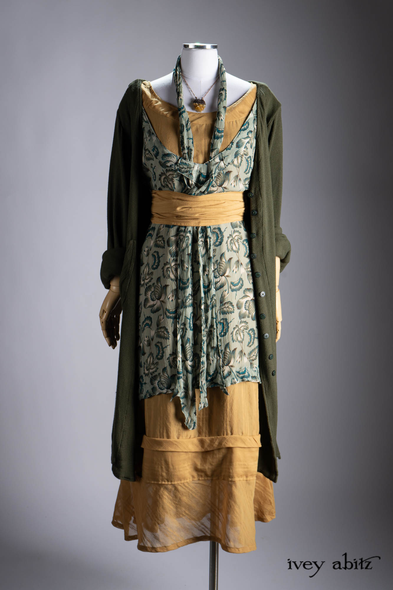Ellis Duster Coat in Idyllic Green Woven Weave; Pierrepont Shirt in Crimson Three-Leaf Silk; Liberte Frock in Riverbank Floral Woven Weave; Cilla Slip Frock in Bark Silky Knit; Hapgood Hat in Bark Washed Woven Hat Weave; Nouvelle Necklace.