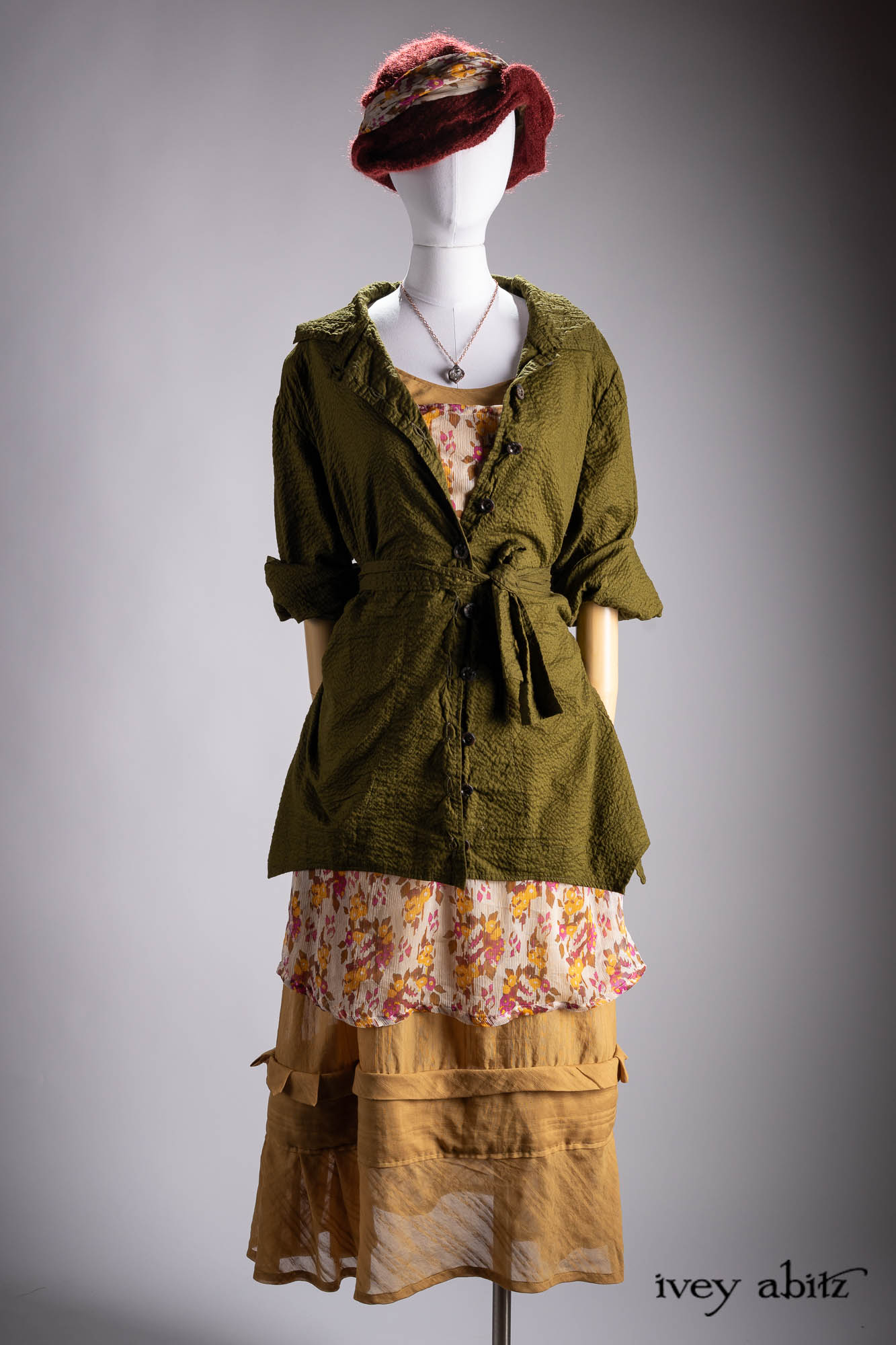 Ellis Duster Coat in Idyllic Green Woven Weave; Pierrepont Shirt in Crimson Three-Leaf Silk; Liberte Frock in Riverbank Floral Woven Weave; Cilla Slip Frock in Bark Silky Knit; Hapgood Hat in Bark Washed Woven Hat Weave; Nouvelle Necklace.