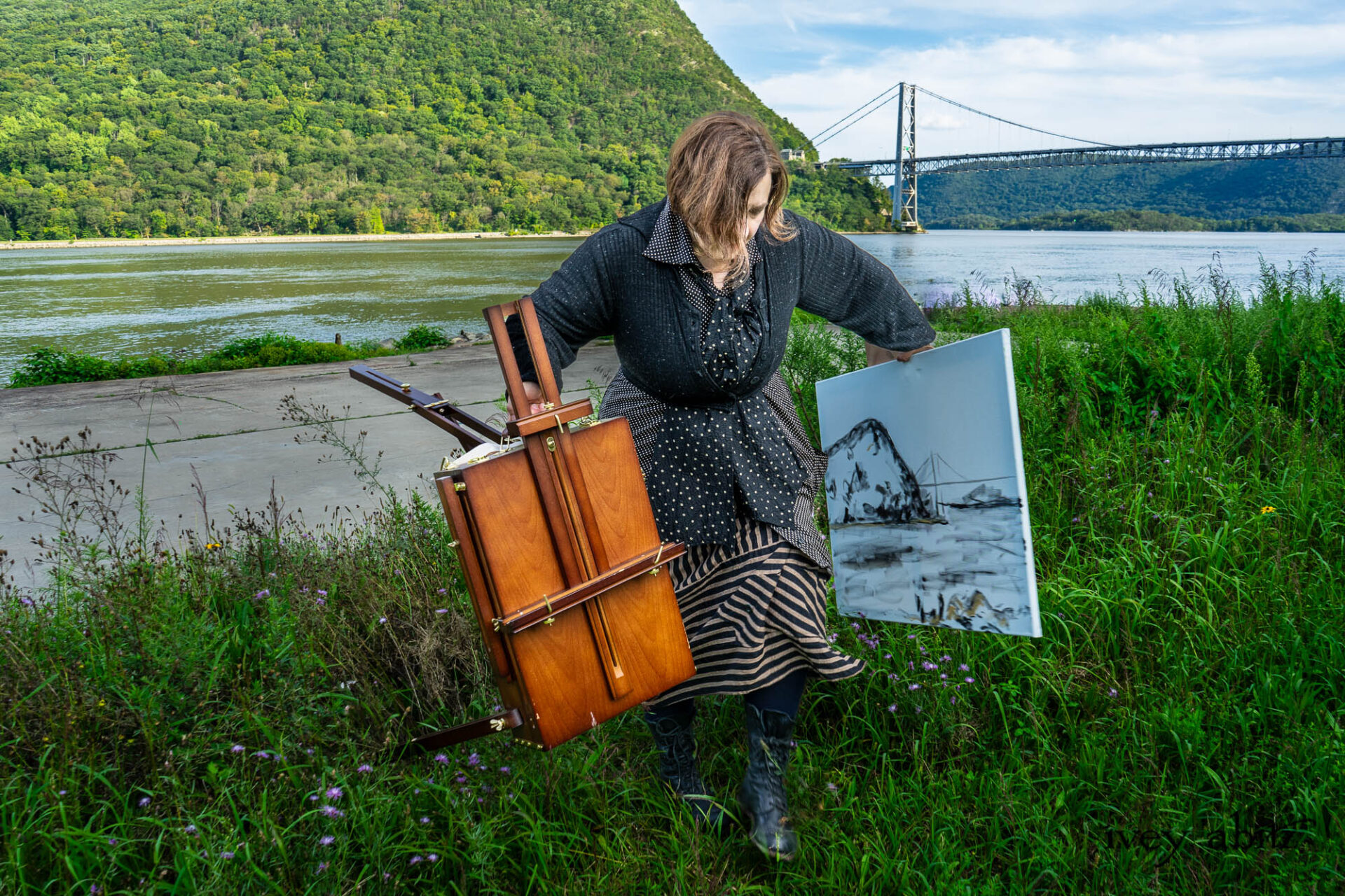 Cynthia Ivey Abitz painting Anthony's Nose and the Bear Mountain Bridge at the banks of the Hudson River. Eugenia Jacket in Mountain Mottled Ribbed Knit Baedeker Shirt Jacket in Mountain and Riverbank Petite Dot Silk Harbourhill Tie in Mountain and Riverbank Puckered Dot Cotton Baedeker Frock in Mountain and Riverbank Stripe Silk Hapgood Hat in Black Plaid Hat Weave Nouvelle Necklace