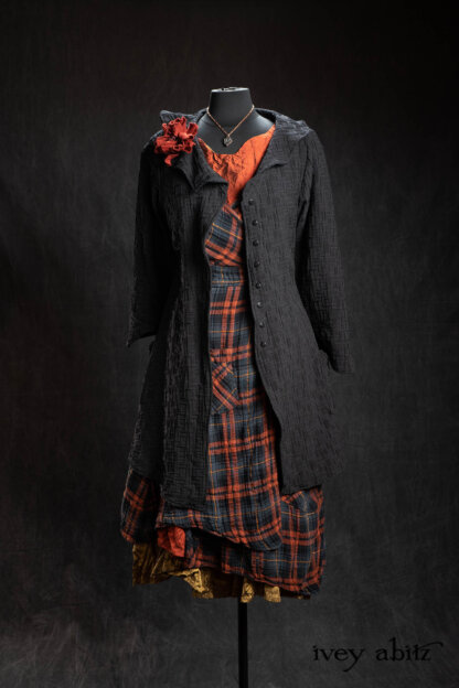 Chevallier Duster Coat in Black Diamond Heirloom Puckered Stretch Weave; Bonheur Brooch in Ruby Sculpted Felt; Chomley Frock in Scottish Gem Plaid Gauze; Inglenook Frock in Scottish Gem Crushed Silk; Inglenook Frock in Brass Crushed Silk; Nouvelle Necklace. - Bespoke clothing by Ivey Abitz.
