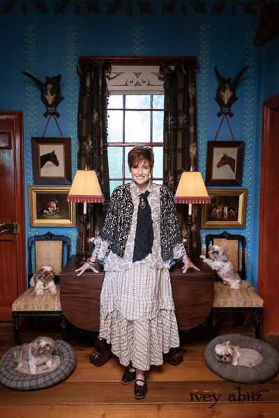 Truitt Shirt in Pearl Floral Crepe de Chine; Truitt Vest in Pearl and Black Diamond Sumptuous Knit; Fitz Necktie in Black Diamond Embroidered Daisy Voile; Heraldry Frock in Pearl Puckered Plaid; Tilly Cardigan in Pearl and Black Diamond Velvet Knit; Essentielle Frock in Signature Black Washed Silk Jersey Knit. - Bespoke clothing by Ivey Abitz. Featuring Carolyn Hennesy with rescue dogs and cats.