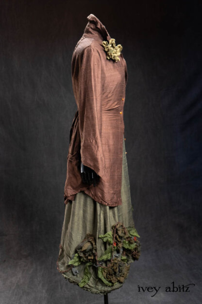 Vanetten Shirt in Earth Washed Textured Silk; Heirloom Necklace; Bonheur Brooch in Olive Quartz Sculpted Felt; Porte Cochere Sash in Olive Quartz Washed Textured Silk; Limited Edition Idyll Frock in Olive Quartz Washed Textured Silk with Handsculpted Floral Embellishments. - Bespoke clothing by Ivey Abitz.