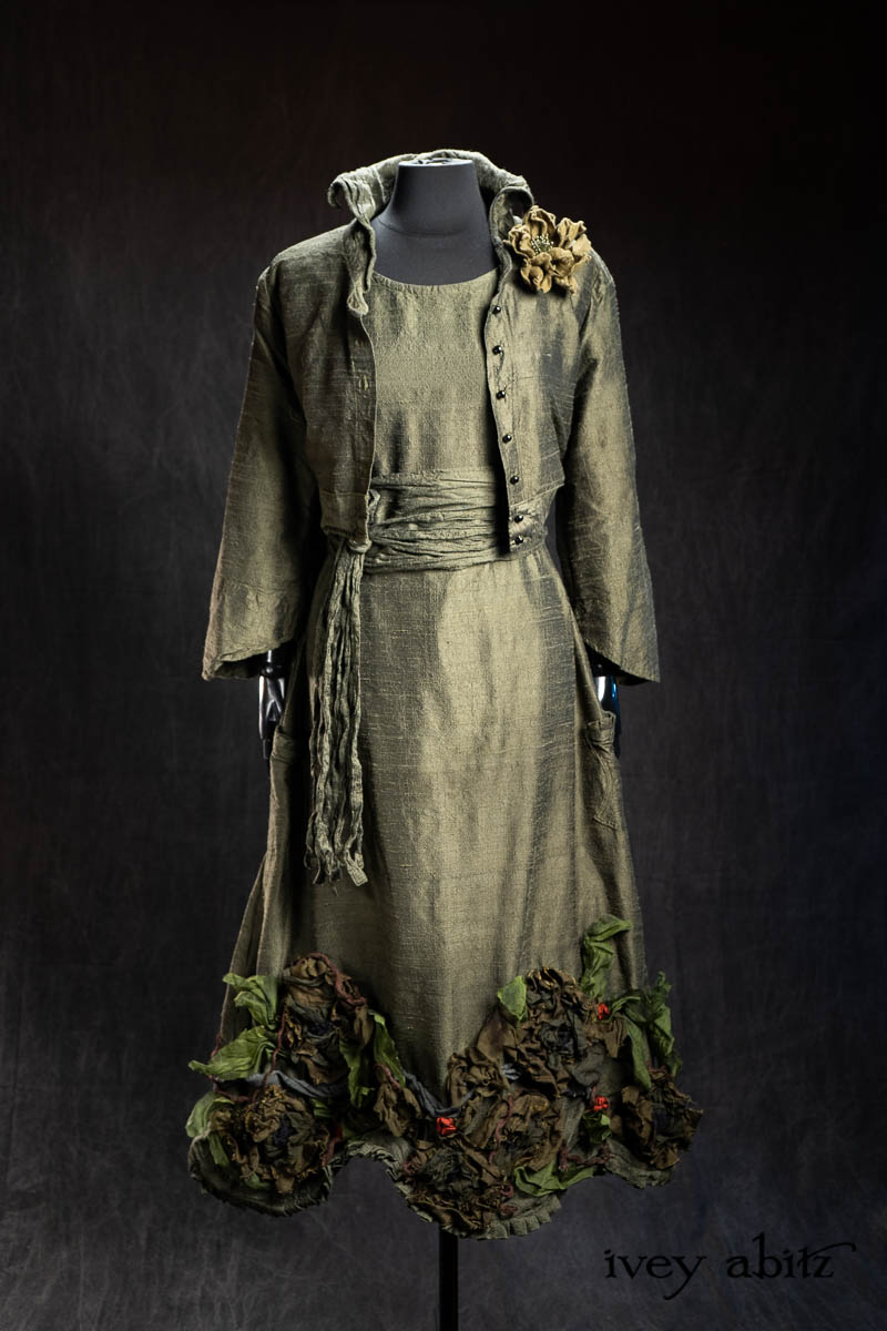 Eugenia Jacket in Olive Quartz Washed Textured Silk; Bonheur Brooch in Olive Quartz Sculpted Felt; Porte Cochere Sash in Olive Quartz Washed Textured Silk; Limited Edition Idyll Frock in Olive Quartz Washed Textured Silk with Handsculpted Floral Embellishments. - Bespoke clothing by Ivey Abitz.