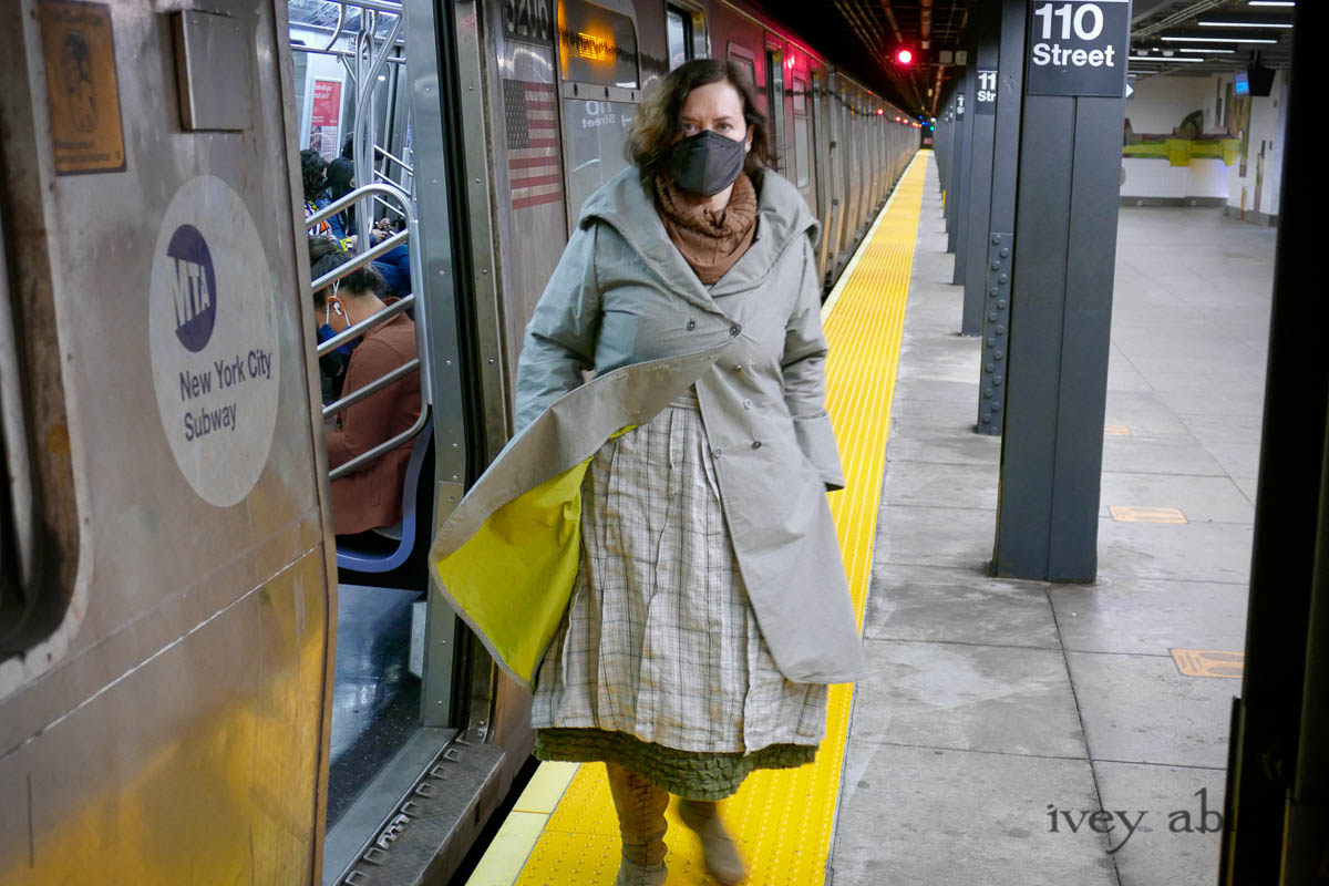 Eleanora Duster Coat in Slate Petite Check Coat Weave; Eleanora Frock in Central Park and Uptown Plaid Linen; Cape Frock in Central Park Washed Linen; Lydia Neck Wrap in Signature Beacon Melange Knit; Bespoke Mask in Slate Washed Knit. - Ivey Abitz Bespoke Clothing