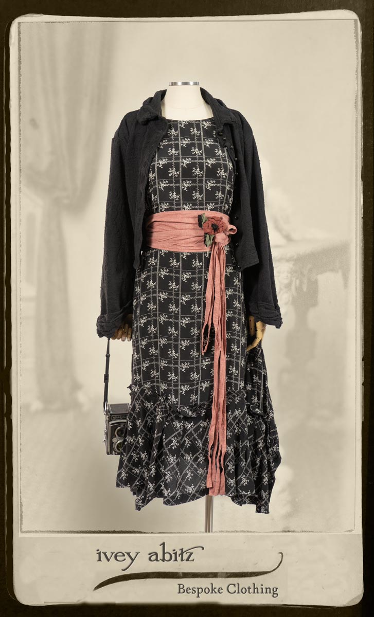 Bertie Jacket in Black Floral Raised Knit; Fairholme Frock in Black and White Washed Silk; Cilla Slip Frock in Signature Black Lightweight Linen Knit; Porte Cochere Sash in Rosy Washed Cotton; Floravinea Brooch in Rosy Washed Crinkled Linen. By Ivey Abitz.