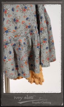 Bertie Jacket in New Sun Softest Knit; Floravinea Brooch in Rosy Washed Crinkled Linen; Tilbrook Frock in Fresh Water Floral Weave; Edenshire Frock in New Sun Washed Linen in High Water Length; Porte Cochere Sash in Rosy Washed Cotton. By Ivey Abitz.