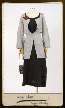 Campanella Shirt Jacket in Black and White Petite Stripe Linen; Bertie Frock in Black Puckered Check Weave; Cilla Slip Frock in Signature Black Lightweight Linen Knit; Floravinea Brooch in Rosy Washed Crinkled Linen. By Ivey Abitz.