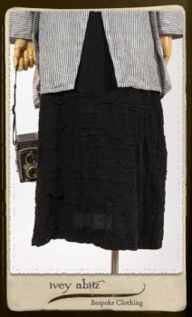 Campanella Shirt Jacket in Black and White Petite Stripe Linen; Bertie Frock in Black Puckered Check Weave; Cilla Slip Frock in Signature Black Lightweight Linen Knit; Floravinea Brooch in Rosy Washed Crinkled Linen. By Ivey Abitz.