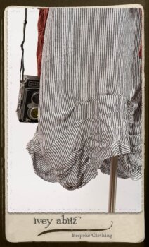 Scattergood Duster Coat in Rosy Washed Crinkled Linen; Scattergood Frock in Black and White Petite Stripe Linen; Floravinea Brooch in Rosy Washed Crinkled Linen. By Ivey Abitz.