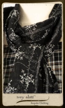 Bramley Frock in Black and White Picture Book Plaid; Clotaire Sash in White on Black Floral Silk Chiffon; Bertie Jacket in Black Floral Raised Knit; Bertie Frock in Black Puckered Check Weave. By Ivey Abitz.