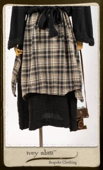 Bramley Frock in Black and White Picture Book Plaid; Clotaire Sash in White on Black Floral Silk Chiffon; Bertie Jacket in Black Floral Raised Knit; Bertie Frock in Black Puckered Check Weave. By Ivey Abitz.