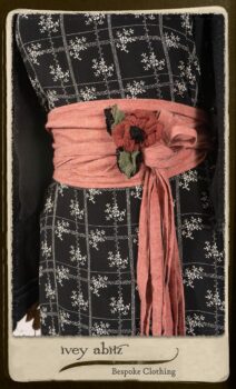 Bertie Jacket in Black Floral Raised Knit; Fairholme Frock in Black and White Washed Silk; Cilla Slip Frock in Signature Black Lightweight Linen Knit; Porte Cochere Sash in Rosy Washed Cotton; Floravinea Brooch in Rosy Washed Crinkled Linen. By Ivey Abitz.